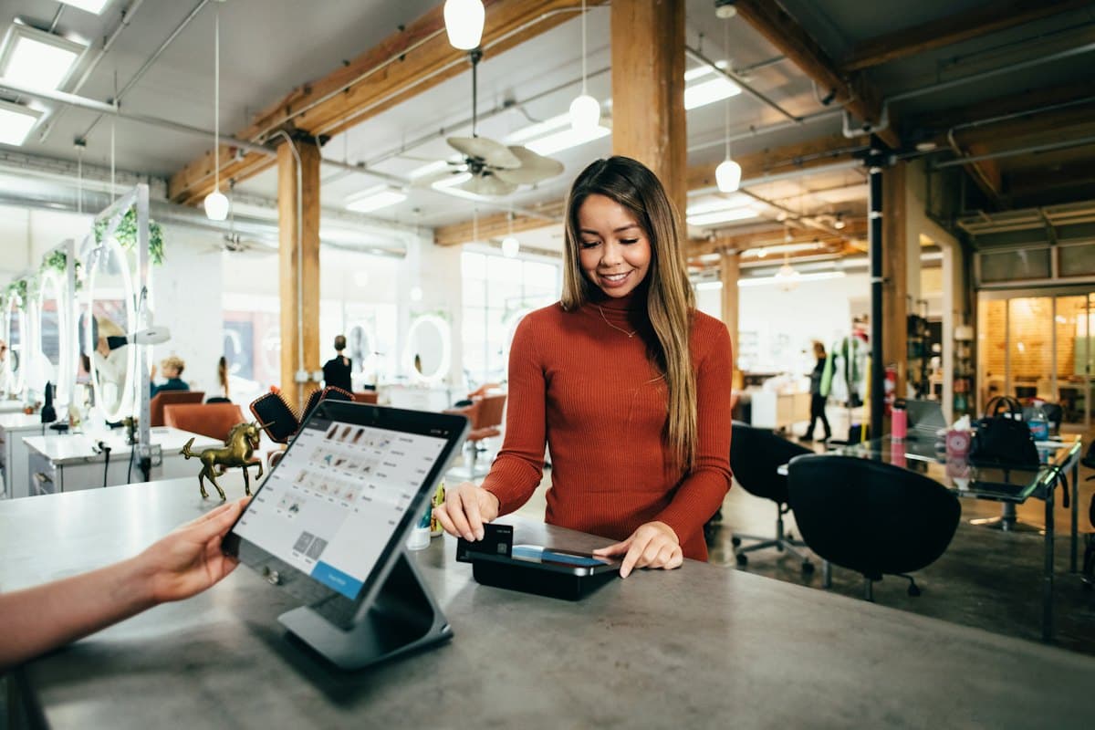 A shop counter with a card terminal and a smiling assistant
